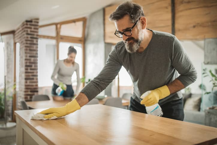 A man and woman cleaning in the kitchen.